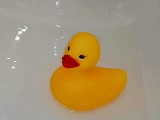 playing in the bathroom with a rubber duck, enjoying the water and bubbles