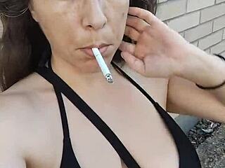 Kelly Kendricks smokes cigarettes outdoors, showing big tits cleavage