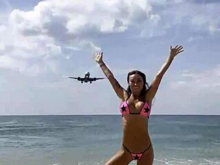 Monika Fox poses seductively in pink bikini on sunny beach.