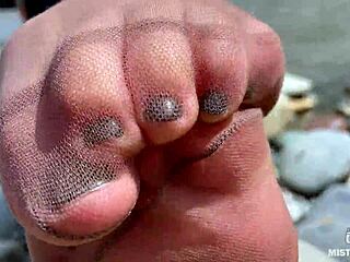 Goddess contrasts tan nylons with cute soles and toes teasing by the riverside outdoors